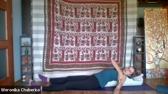 Weronika lies over a bolster, explaining a restorative yoga class to her online students